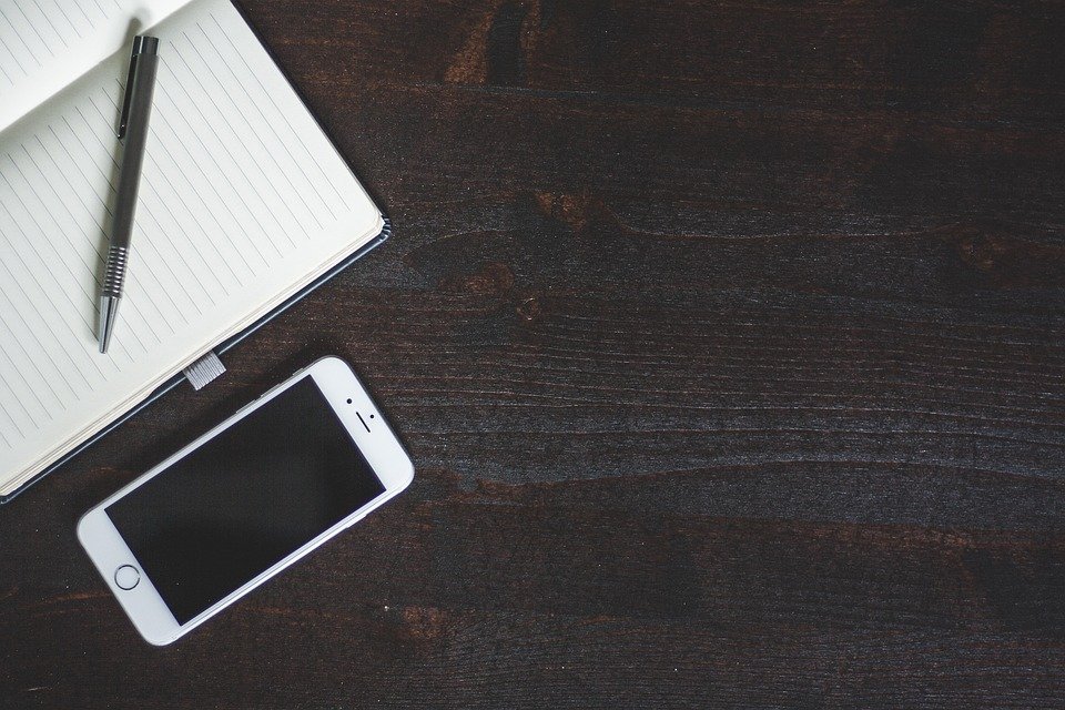 A phone, notepad and pen on a desk